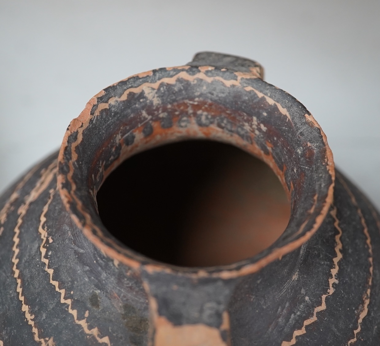 A Chinese neolithic pottery two handled jar - 14cm tall. Condition - fair to good, Provenance: the vendor‘s parents lived in Hong Kong from 1947 and bought the jar from a specialist dealer before 1980.